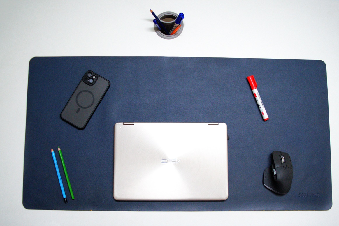 Laptop, wireless mouse and iPhone on a blue colored desk mat