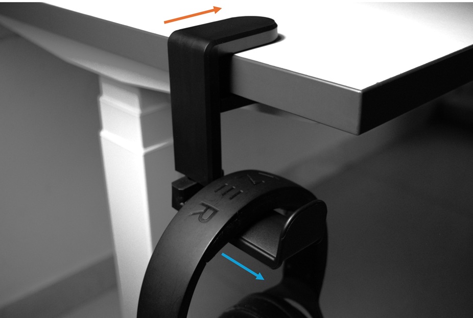 Black headphone hanger clamped to the left side of a white desk