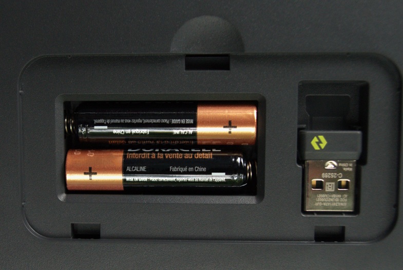Battery slot on the back of the Logitech Wave Keys keyboard with two AAA batteries and a place for the wireless Bolt receiver